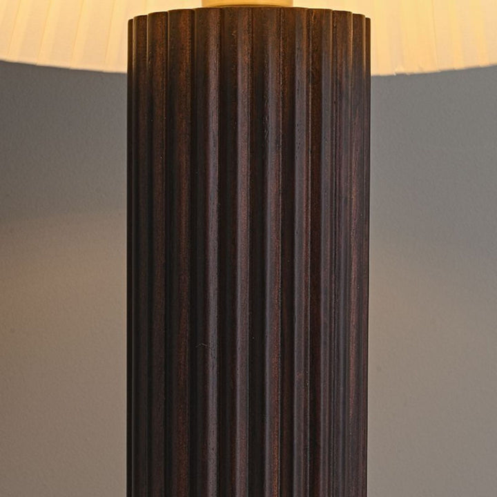 Detaljbild på Aristo bordslampas räfflade fot i mörkt trä med tydlig struktur och gedigen finish.