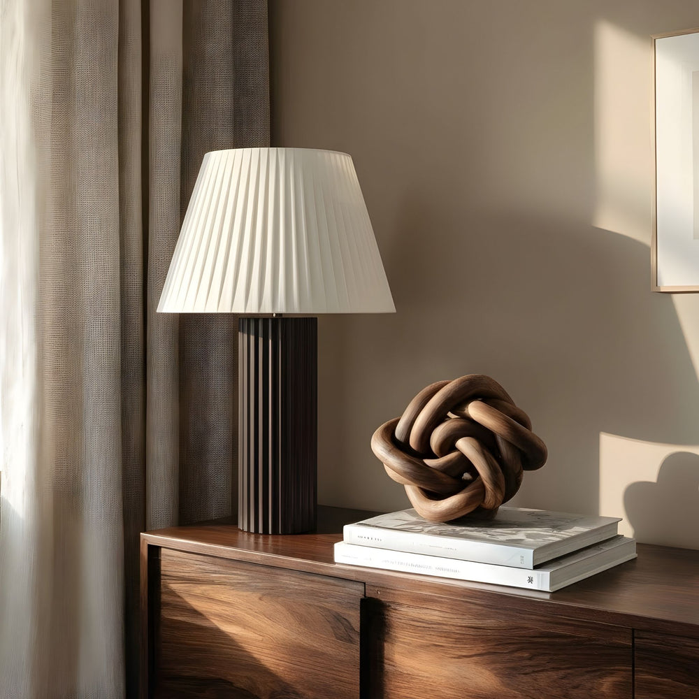 Bordslampa Aristo på sidobord i vardagsrum, kombinerar veckad lampskärm med mörk träfot för en exklusiv känsla.