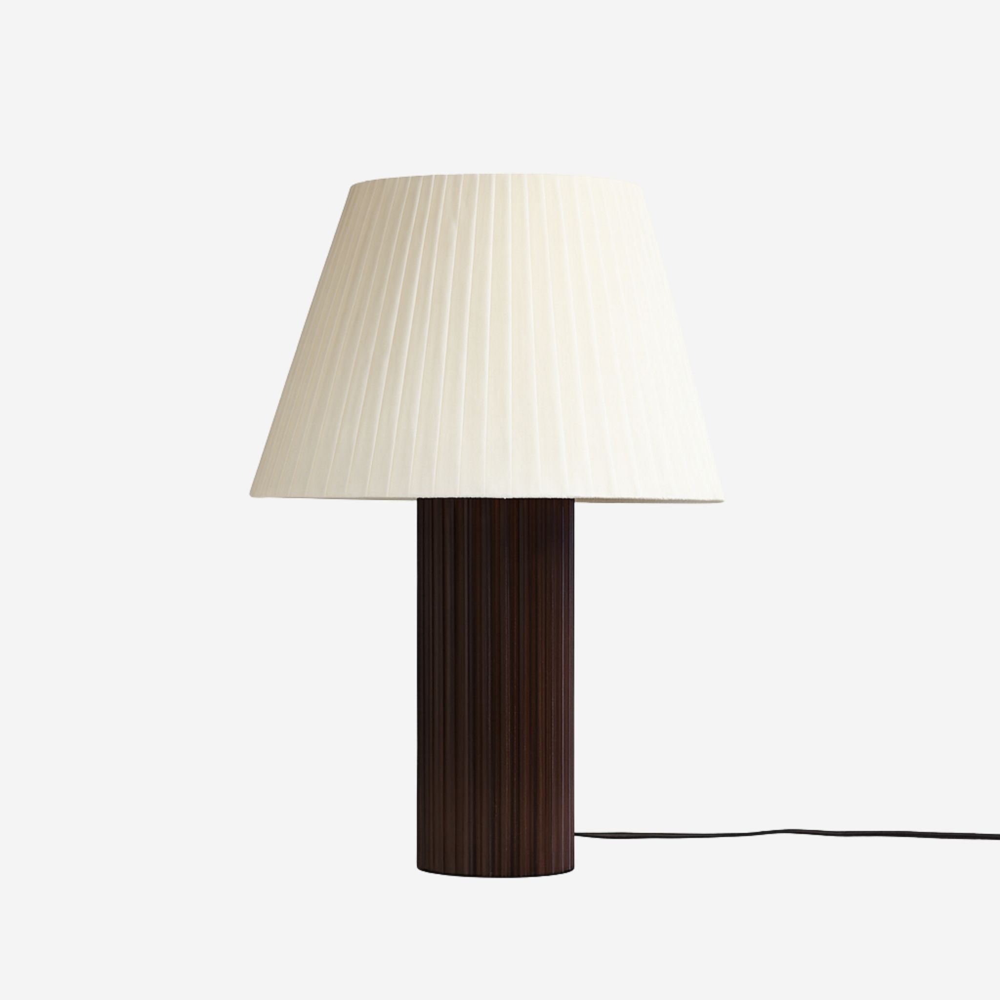 Bordslampa Aristo med veckad vit lampskärm och räfflad fot i mörkt trä, tidlös design för vardagsrum och sovrum.