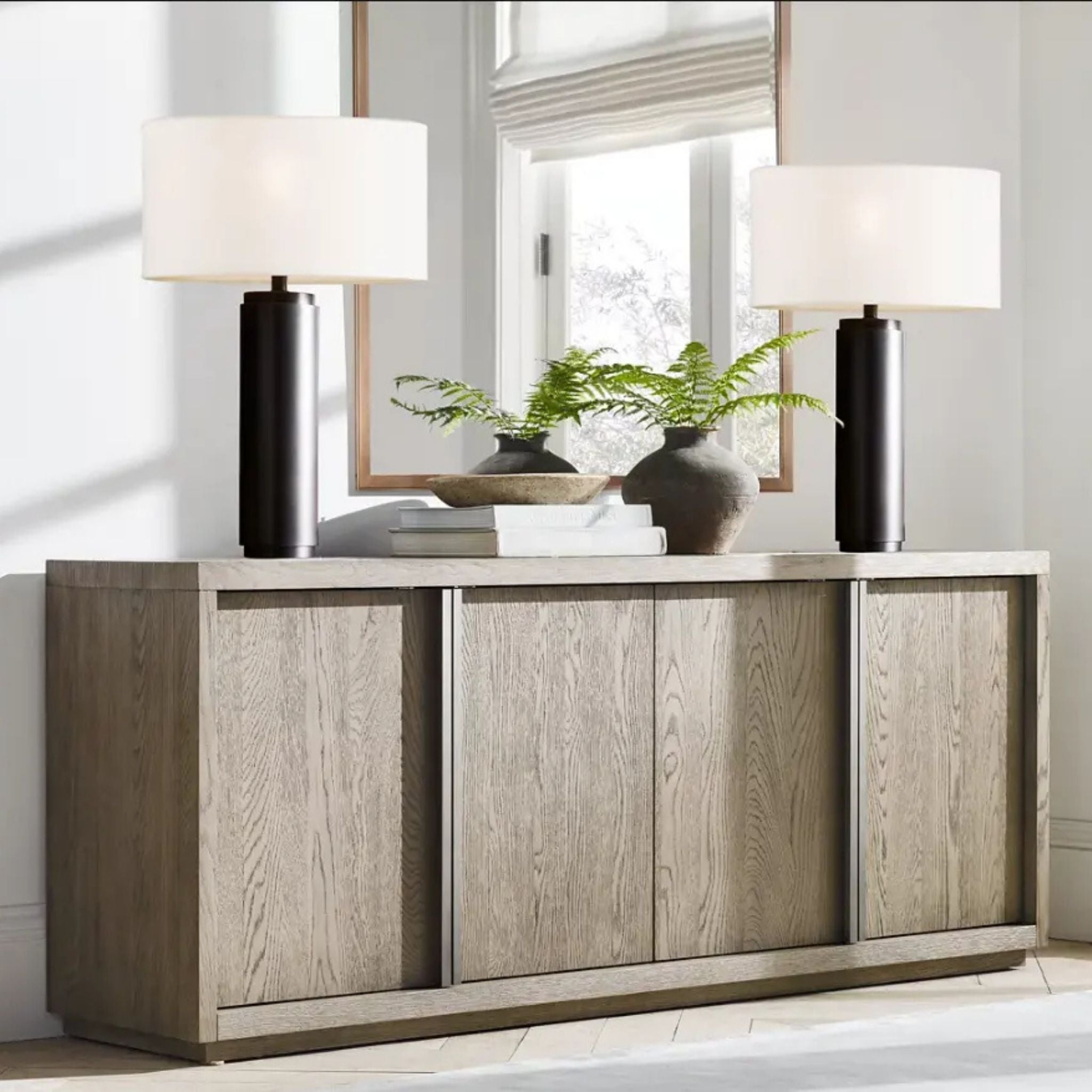 Två bordslampor Atlas i svart med vita tygskärmar placerade symmetriskt på sideboard i vardagsrum