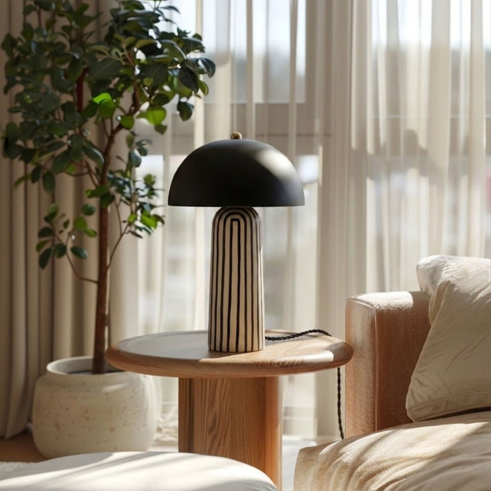 Bordslampa Cavern Zebra med svart skärm och mönstrad fot på sidobord i vardagsrum med växt