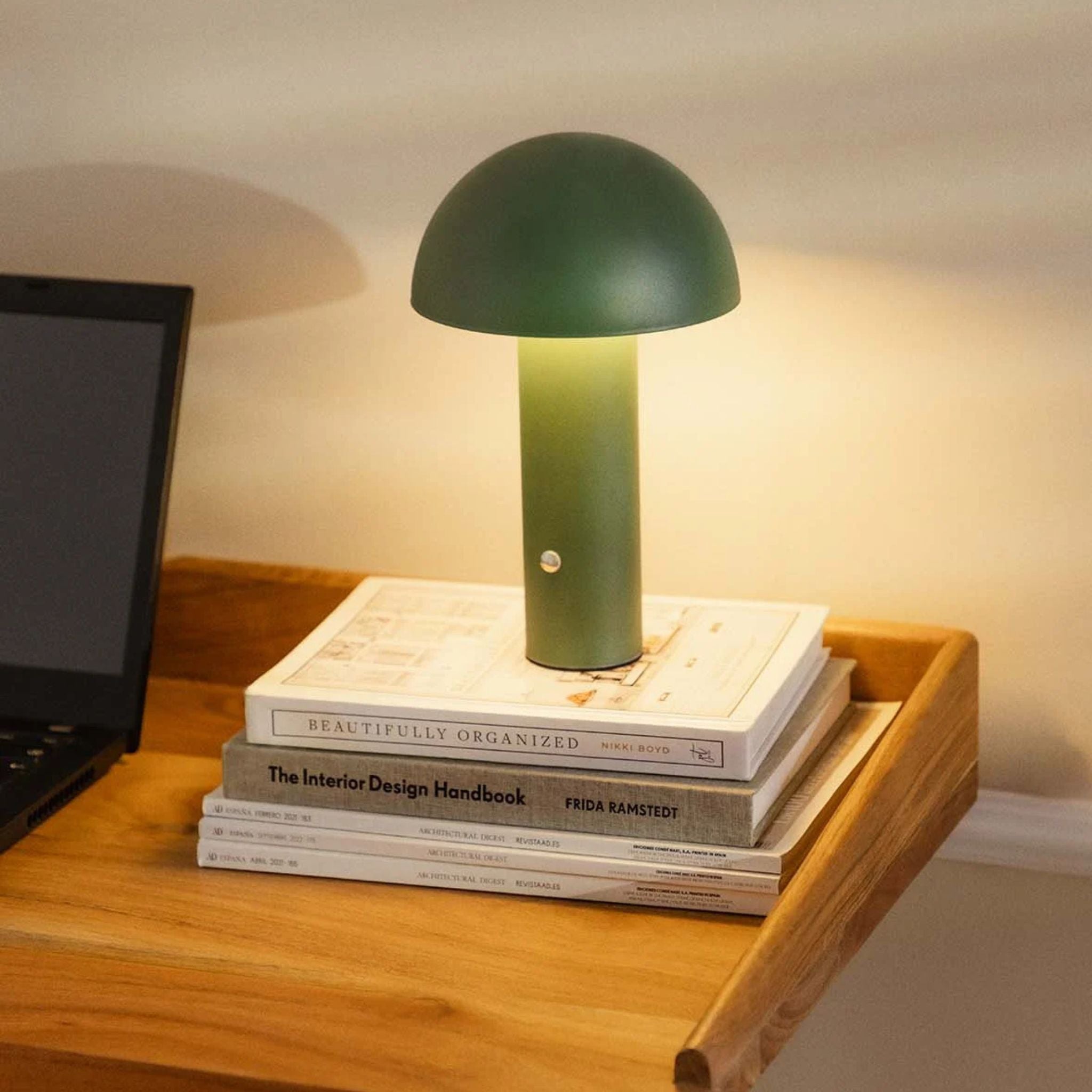 Närbild på grön bordslampa De Mesa i metall placerad på träbord med varm belysning