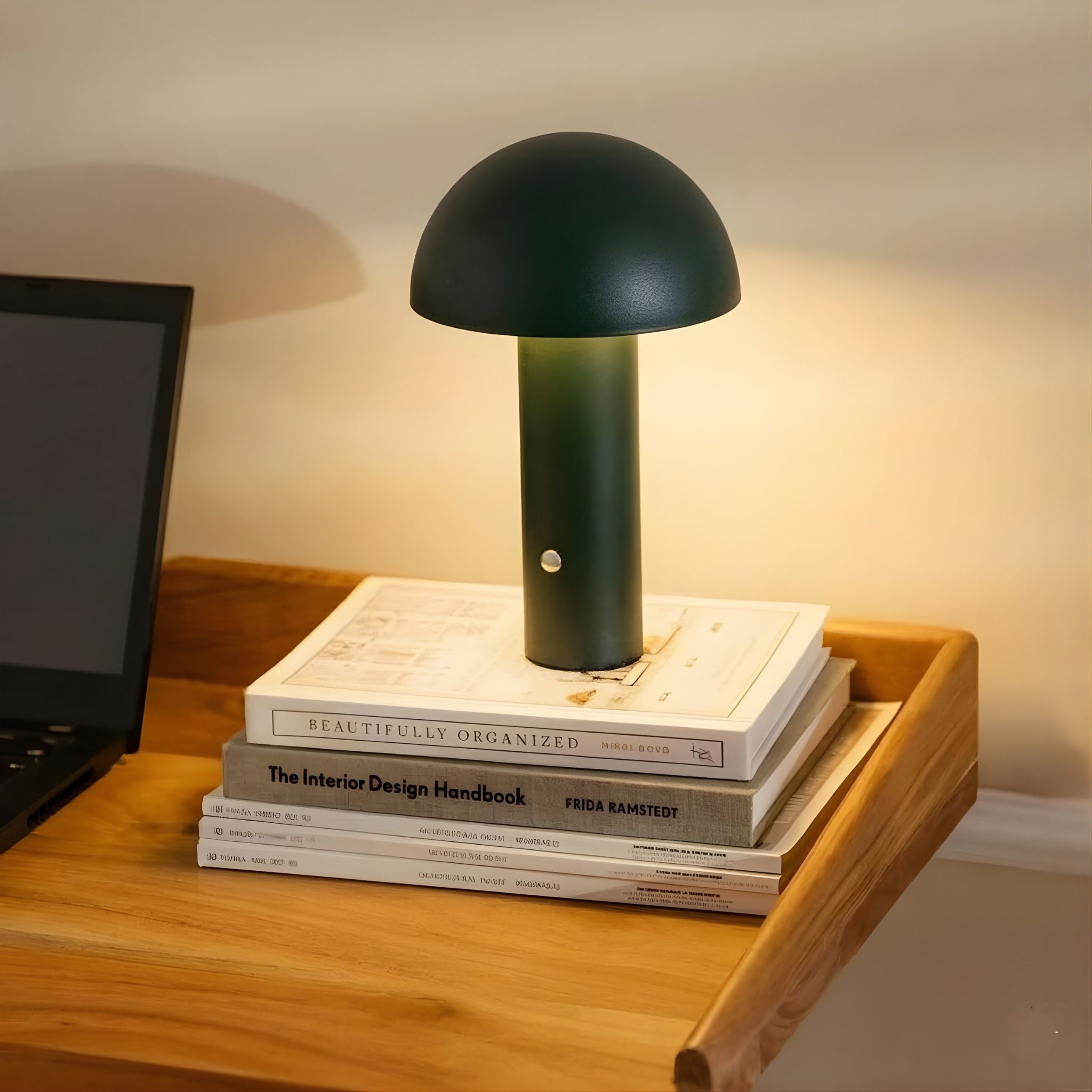 De Mesa bordslampa i grön finish placerad på böcker på skrivbord i en stilren arbetsplats med varm belysning och skandinavisk design.