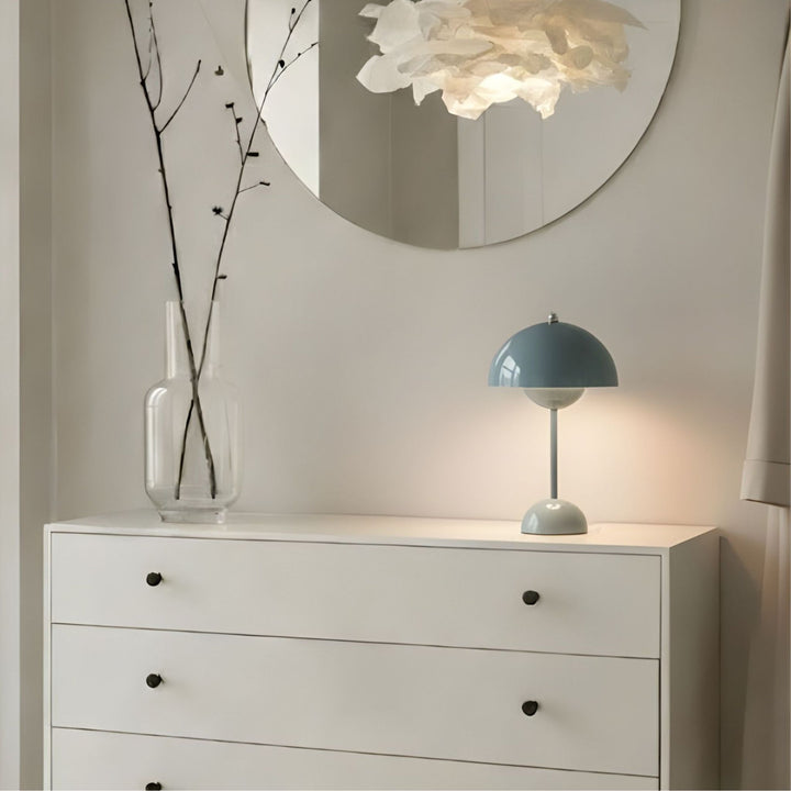 Bordslampa Flowerbud i blå design placerad på vit byrå under rund spegel i stilrent skandinavisk hall med mjuk och dekorativ belysning.
