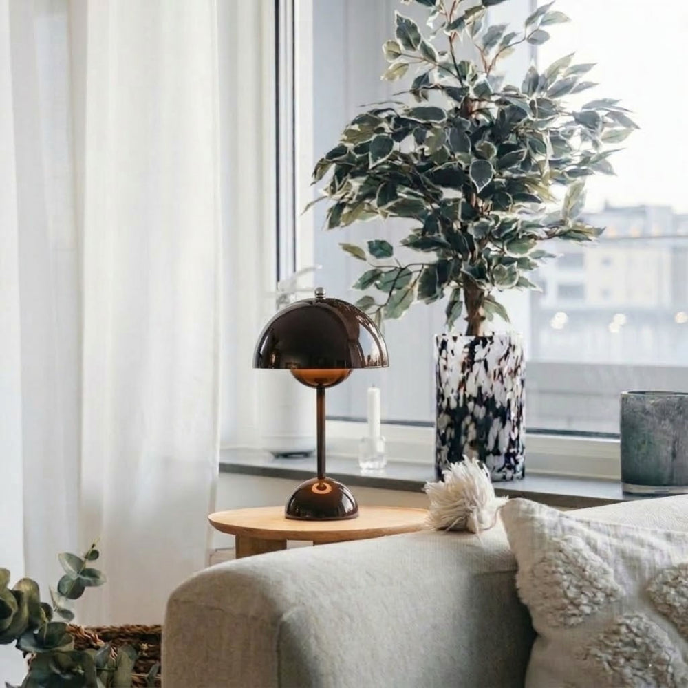 Flowerbud bordslampa i brun finish med rund skärm, placerad på sidobord vid fönster i stilrent vardagsrum med skandinavisk inredning och växter