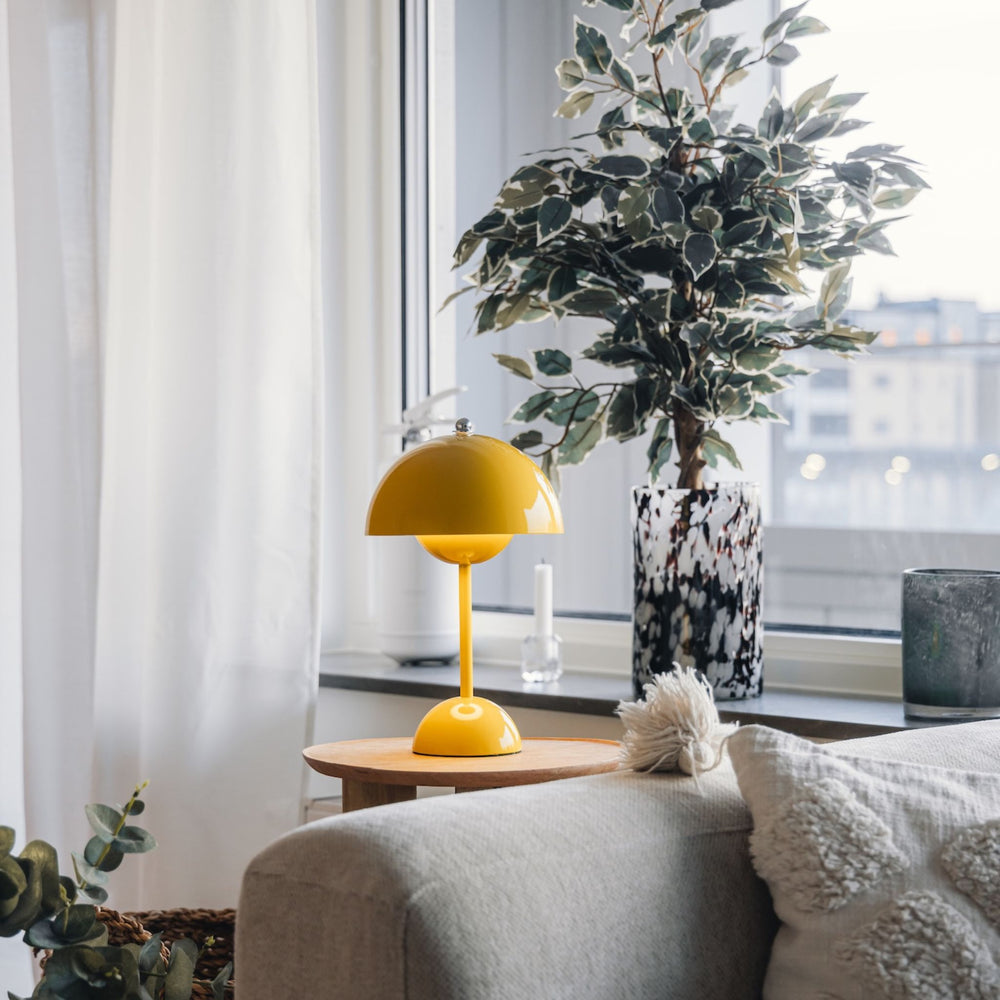 Gul Flowerbud bordslampa placerad vid fönster som färgstark inredningsdetalj