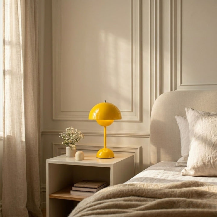 Gul bordslampa Flowerbud på sängbord i sovrum med mjuka beige textilier och varm belysning
