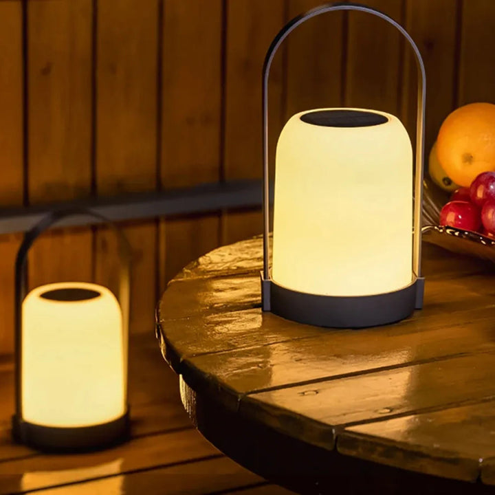 Portabel bordslampa Halo på träbord tillsammans med flera ljuspunkter, skapar en inbjudande och varm atmosfär.