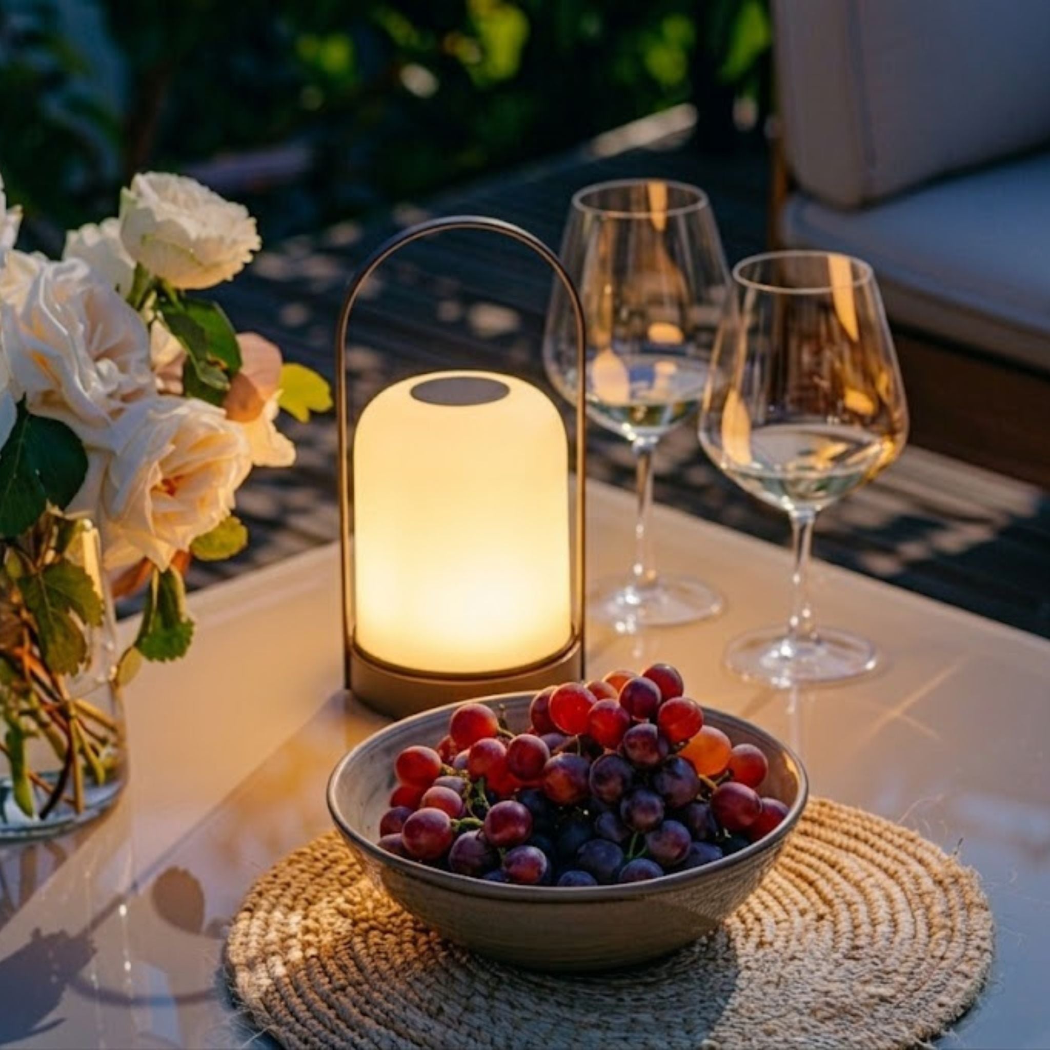 Portabel bordslampa Halo tänd på terrassbord i kvällsljus med vinglas och dukning
