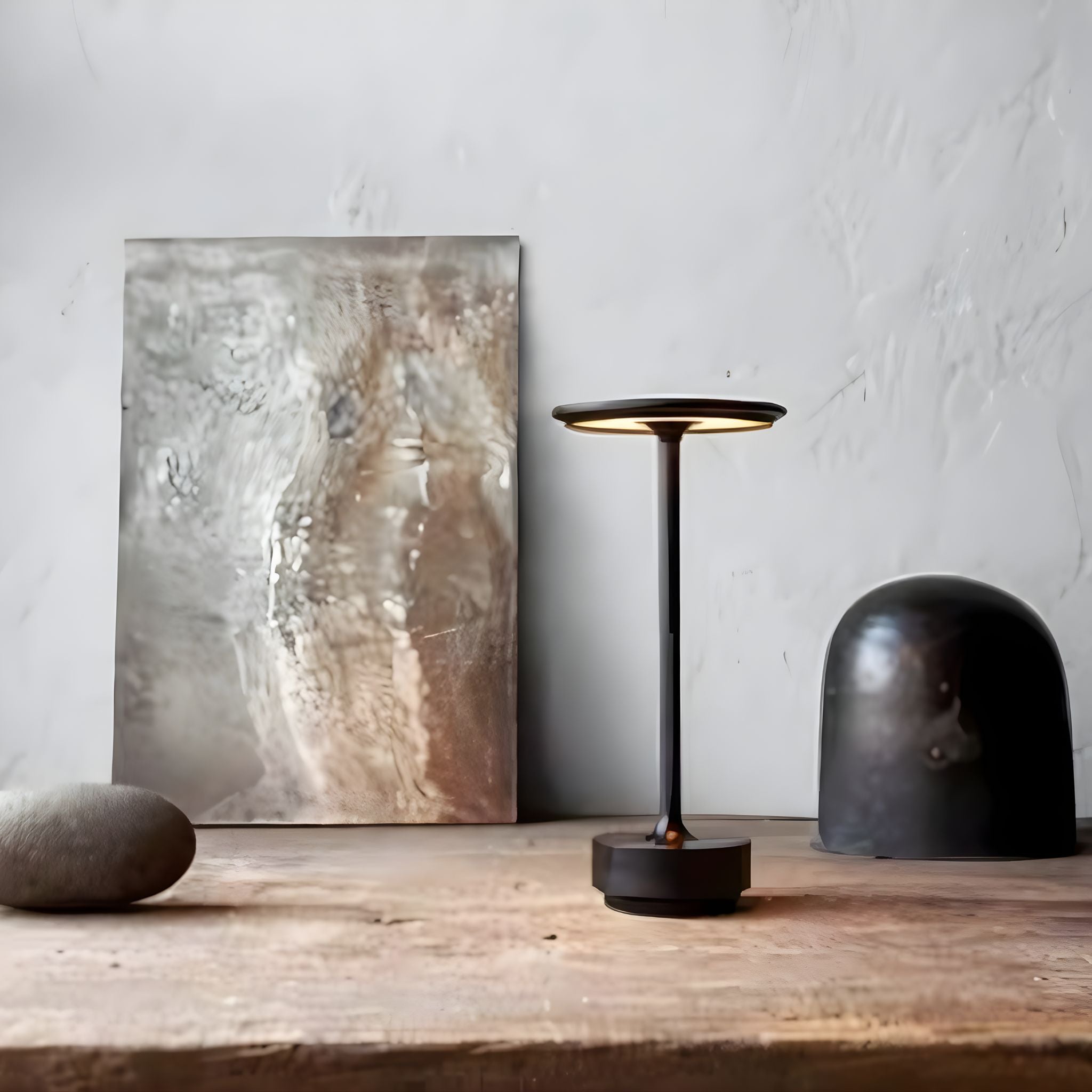 Bordslampa Iron i minimalistisk designmiljö, kombinerad med konst och naturmaterial för ett exklusivt uttryck.