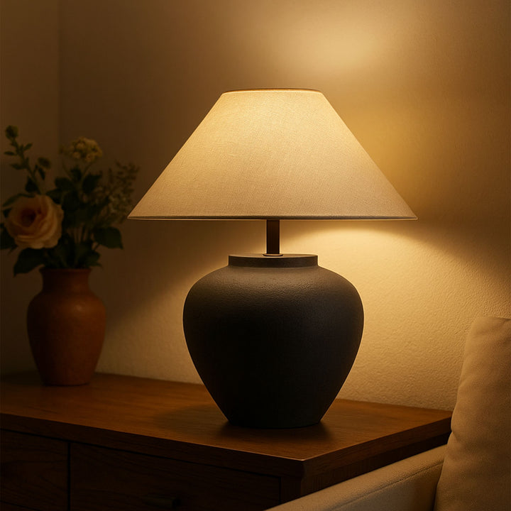 Bordslampa Noir som stämningsbelysning i rum med mjuka textilier och lugn, varm atmosfär.
