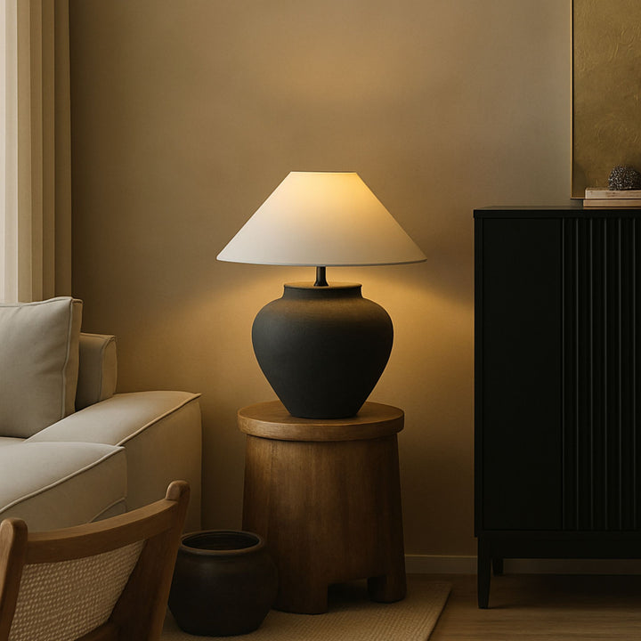 Bordslampa Noir placerad på sidobord i vardagsrum med varm belysning och harmonisk, neutral inredning.