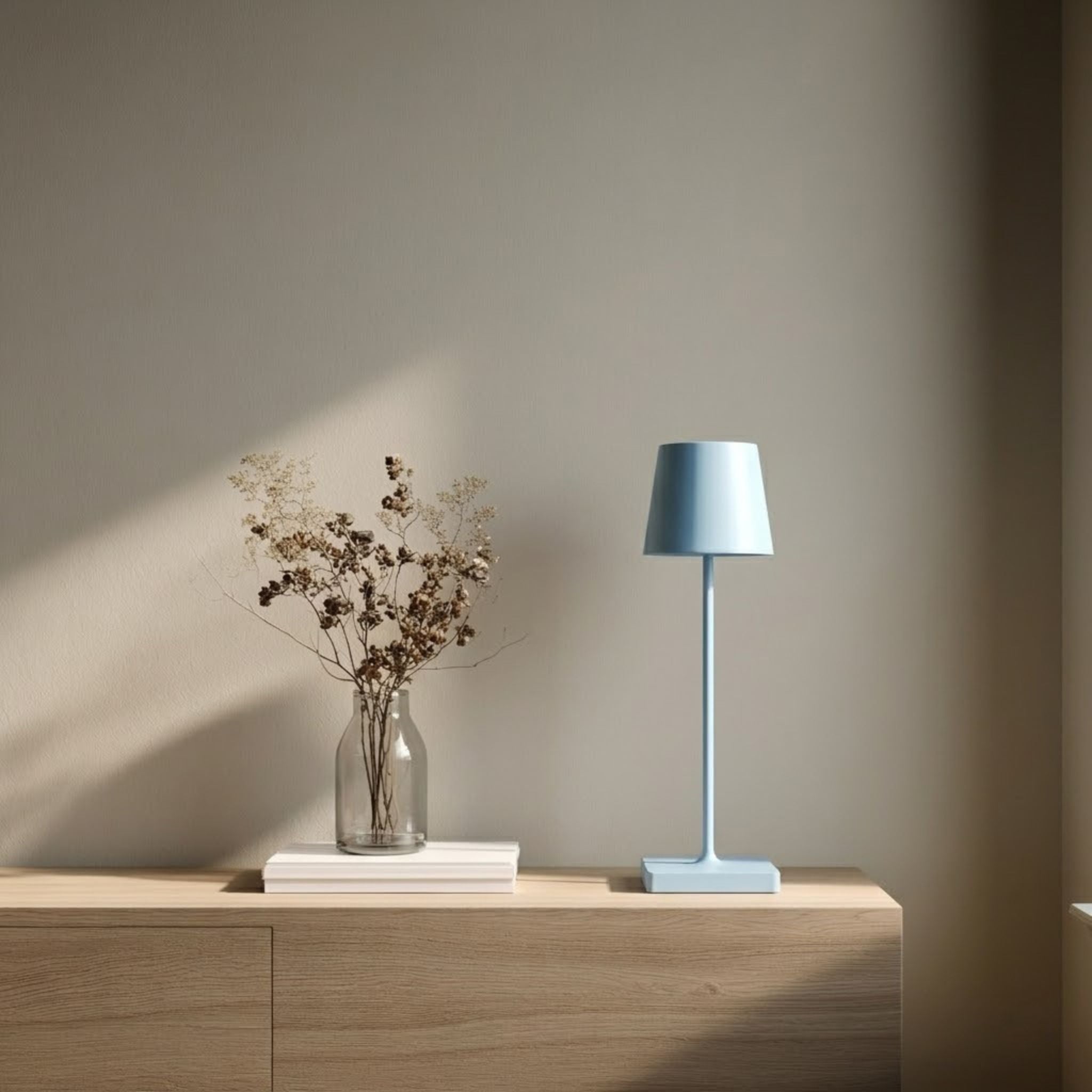 Oslo bordslampa i blå med minimalistisk design placerad på sidobord i en ljus och stilren skandinavisk miljö.