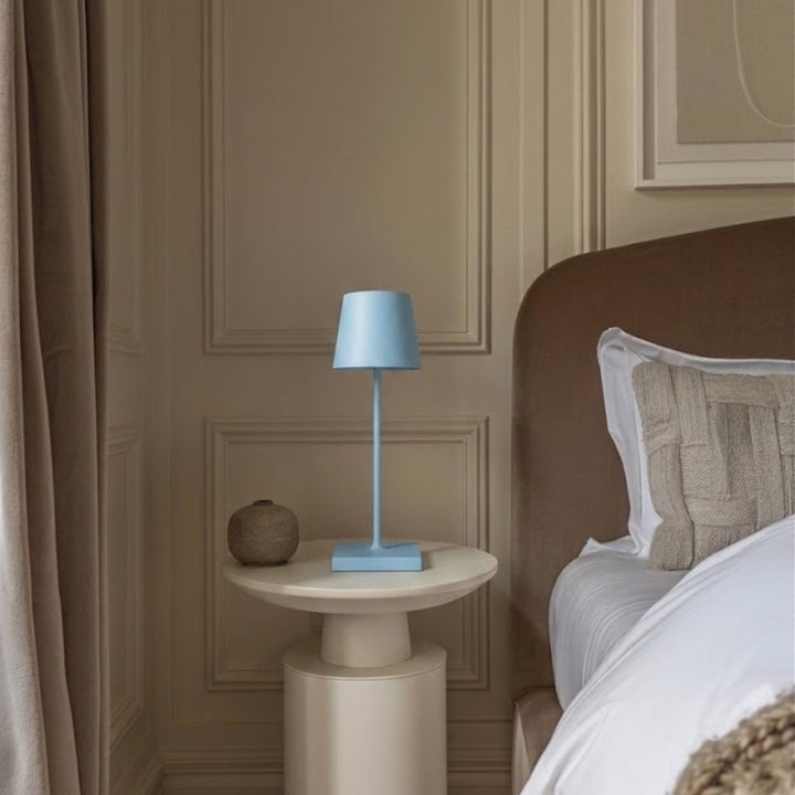 Blå bordslampa Oslo i metall på sängbord i sovrum med mjuk beige textilier