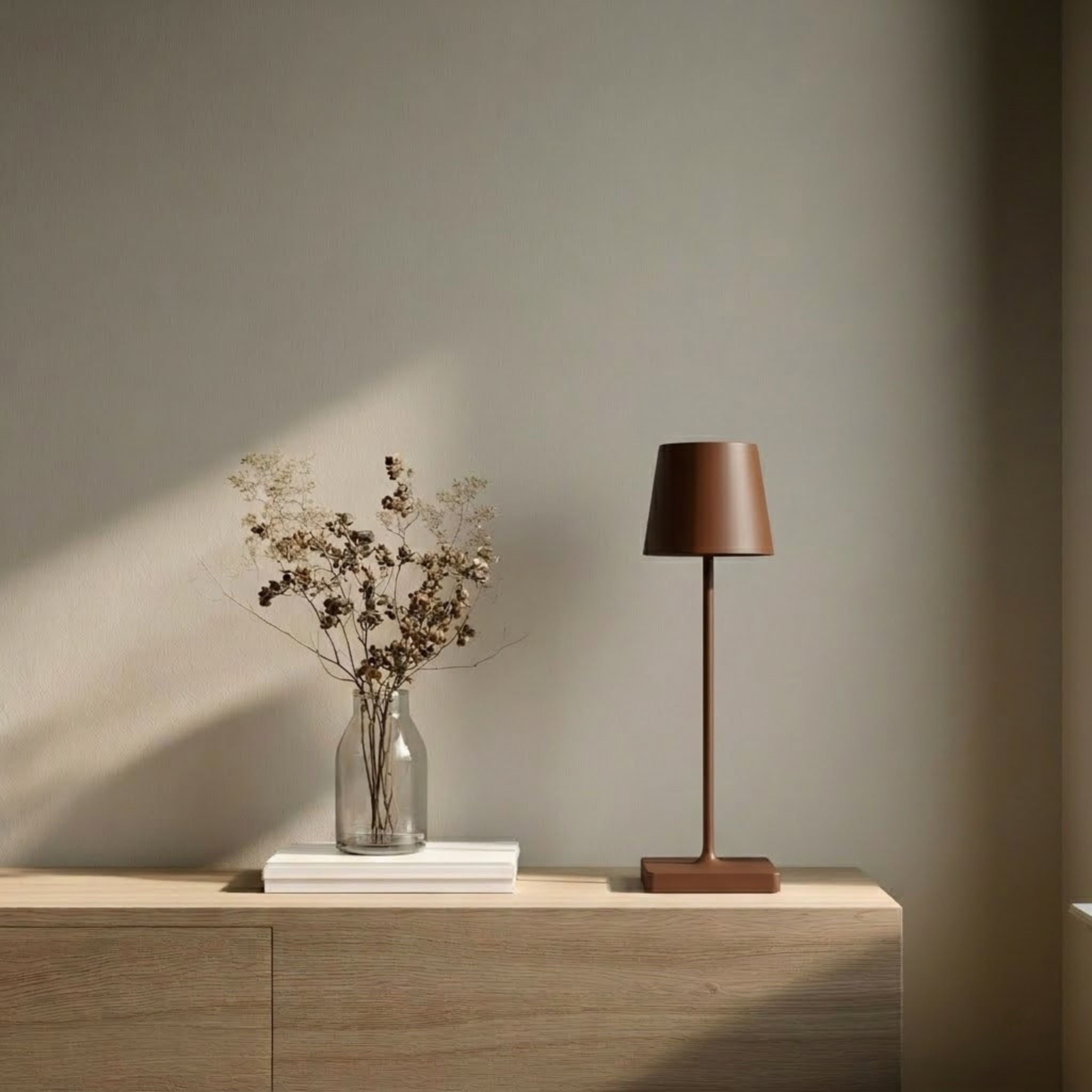 Oslo bordslampa i brun med minimalistisk design placerad på sidobord i en ljus och stilren skandinavisk miljö.