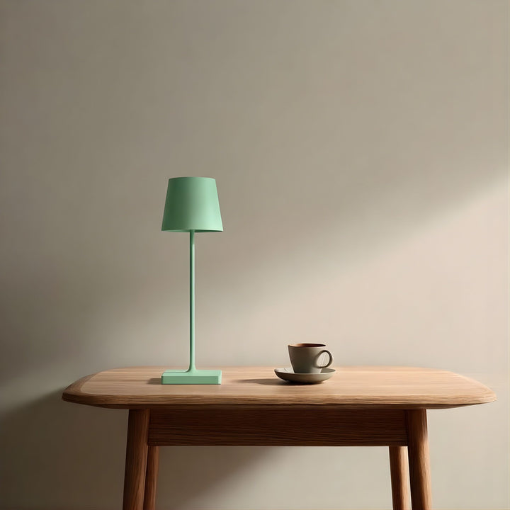 Oslo bordslampa i grön kulör placerad på träbord tillsammans med kopp i avskalad och minimalistisk skandinavisk miljö.
