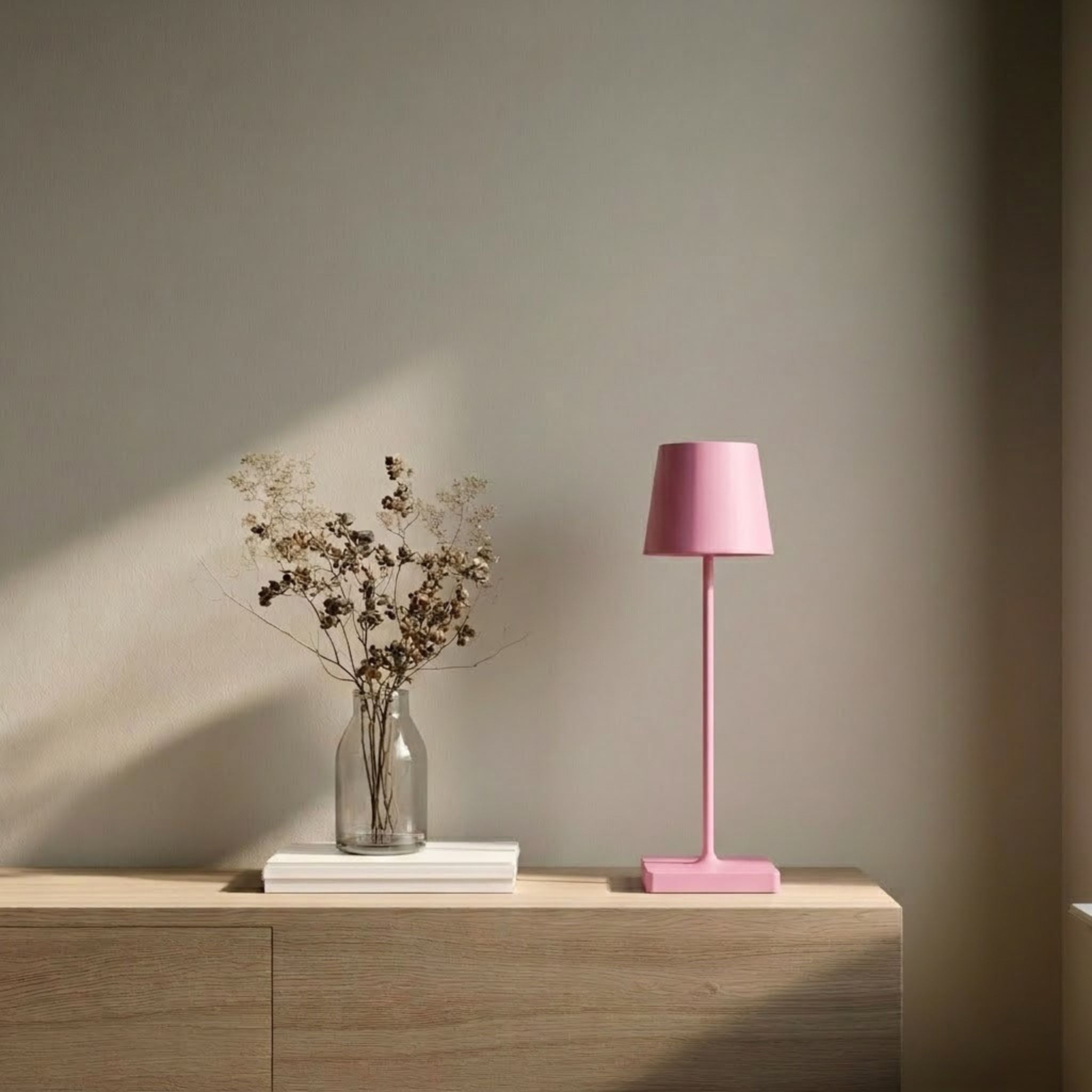 Oslo bordslampa i rosa med minimalistisk design placerad på sidobord i en ljus och stilren skandinavisk miljö.
