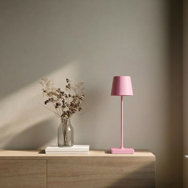 Oslo bordslampa i rosa med minimalistisk design placerad på sidobord i en ljus och stilren skandinavisk miljö.