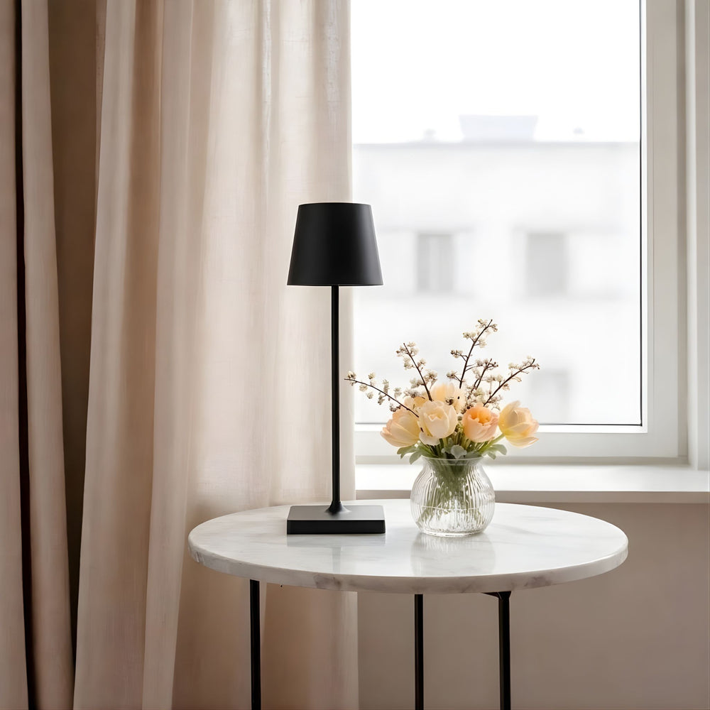 Oslo bordslampa i svart färg på marmorbord vid fönster med neutrala textilier och blommor, i minimalistisk skandinavisk inredning.