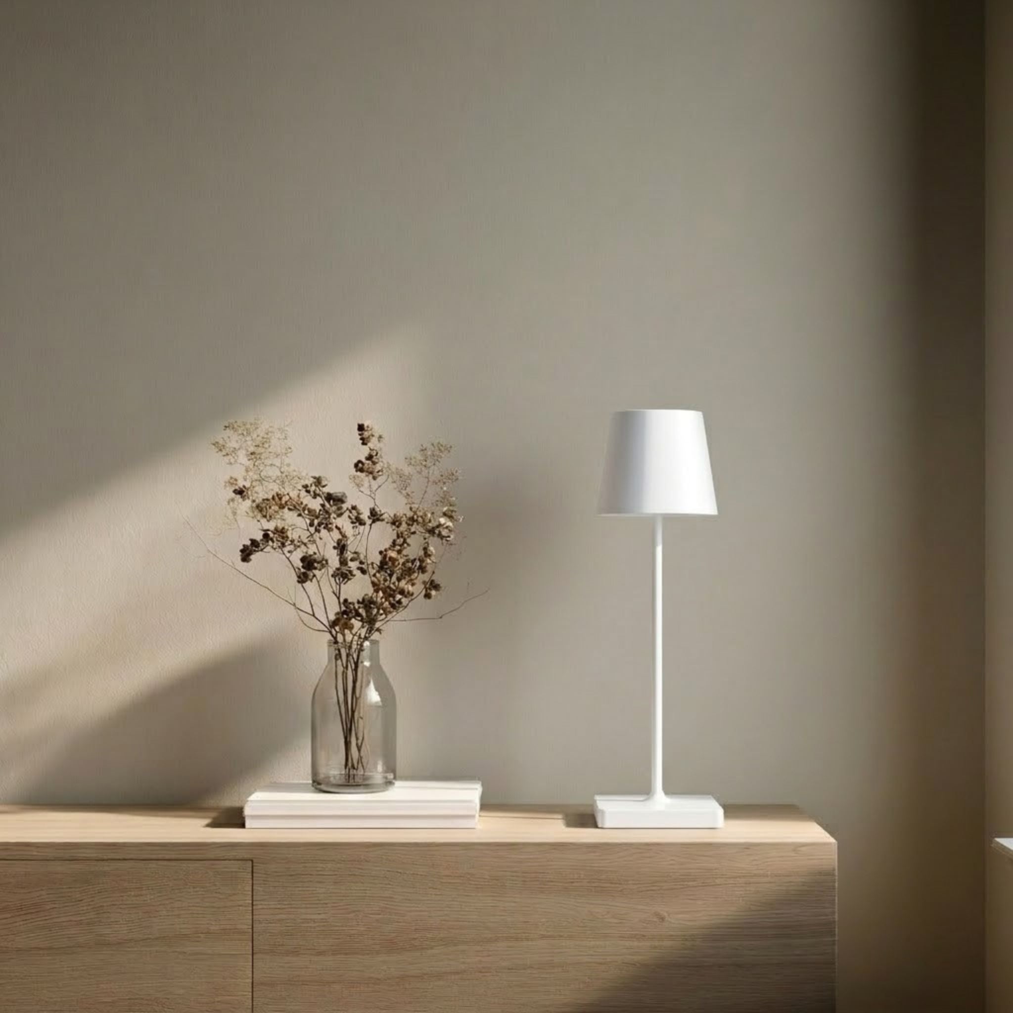 Oslo bordslampa i vit med minimalistisk design placerad på sidobord i en ljus och stilren skandinavisk miljö.