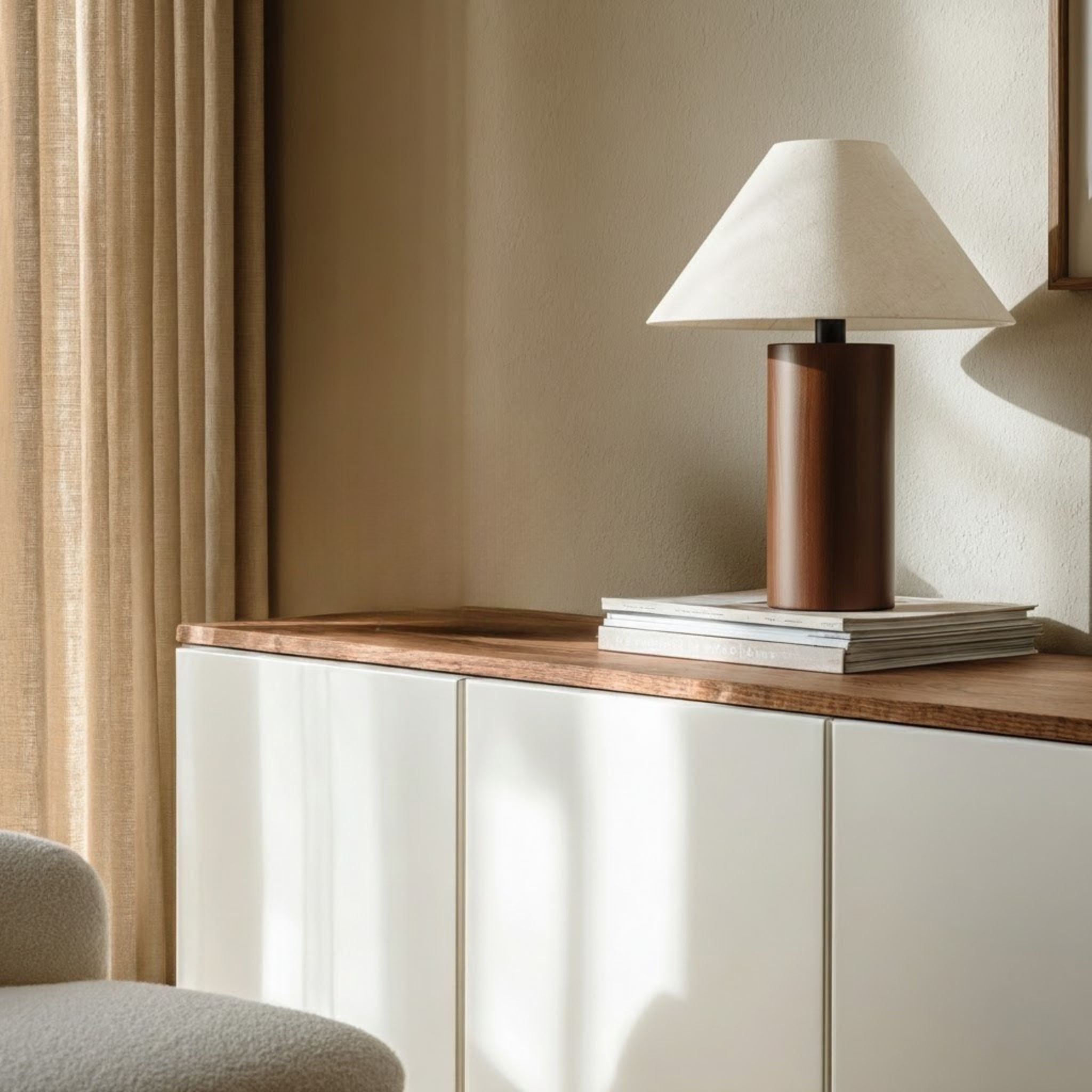 Sirocco bordslampa med träfot och linneskärm i linnekräm på sideboard med böcker – dekorativ bordslampa i nordisk design som ger varmt, behagligt ljus i moderna hem.