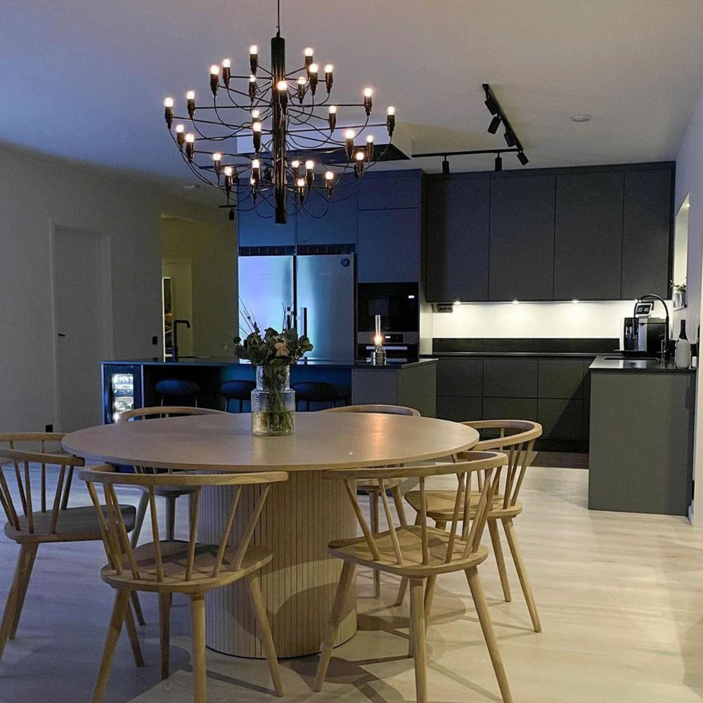 Elegant Ljuskrona 30 i svart placerad över runt matbord i modern matsal med varm och stämningsfull belysning