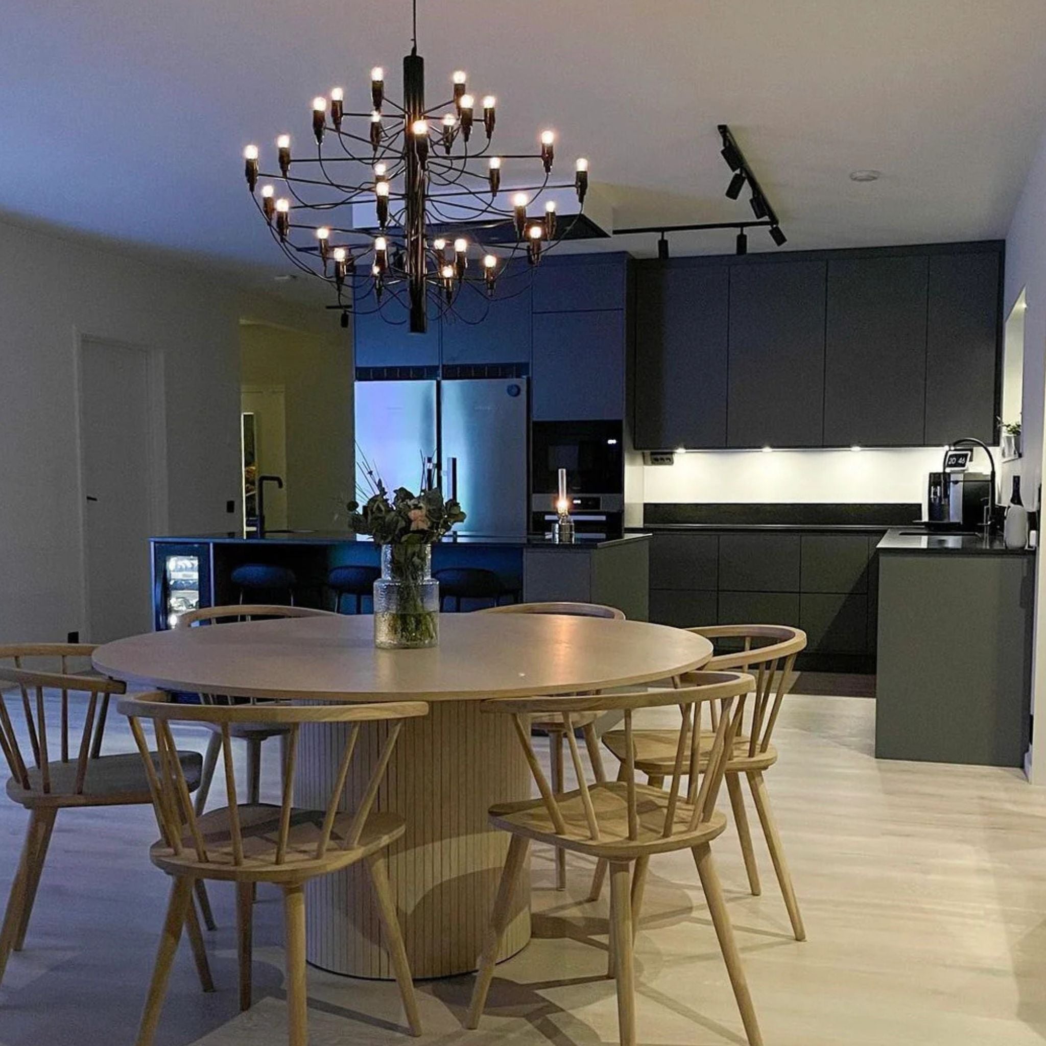 Elegant Ljuskrona 30 i svart placerad över runt matbord i modern matsal med varm och stämningsfull belysning