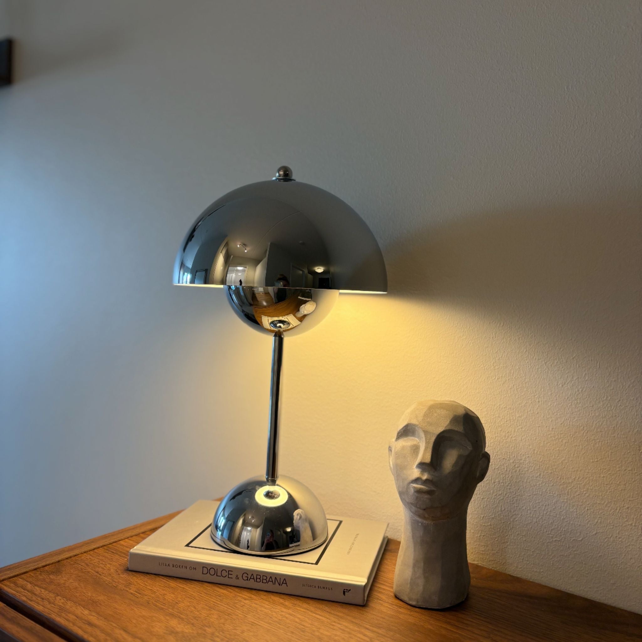 flowerbud bordslampa i krom på sidobord med varm belysning i modern skandinavisk inredning