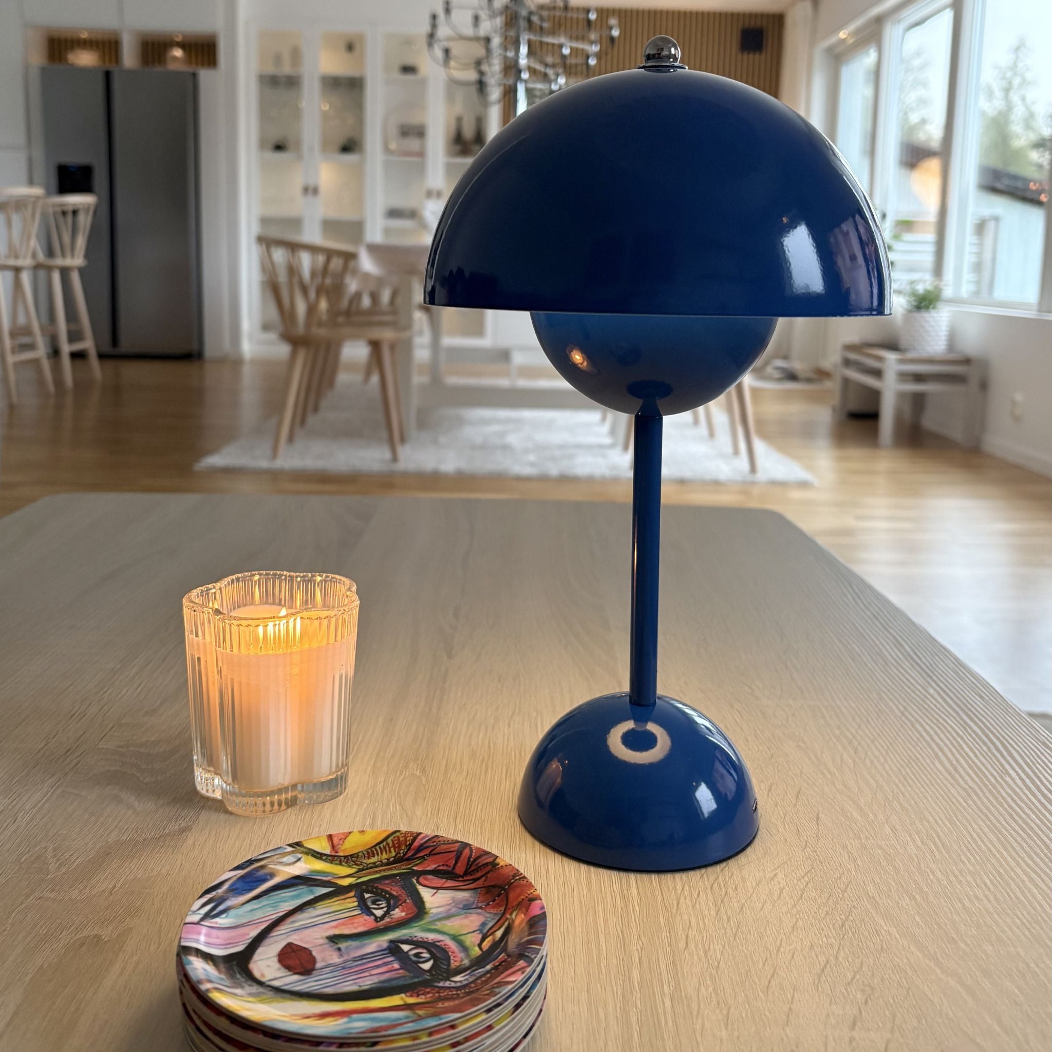 Blå Flowerbud portabel bordslampa i modern design på träbord med levande ljus i skandinaviskt vardagsrum