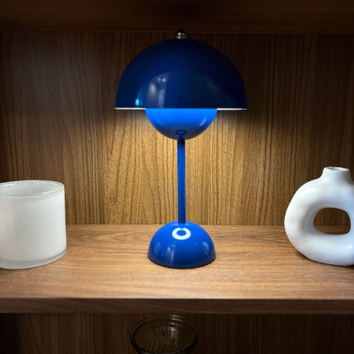 portabel bordslampa Flowerbud mörkblå med varm belysning på hylla i modern skandinavisk inredning