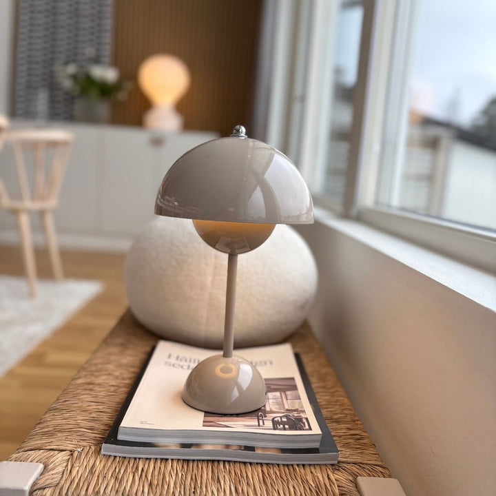 Flowerbud portabel bordslampa i greige på bänk vid fönster