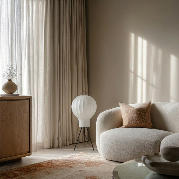 Golvlampa Bubble med rund vit lampskärm släckt i vardagsrum med beige soffa och stora gardiner i bakgrunden