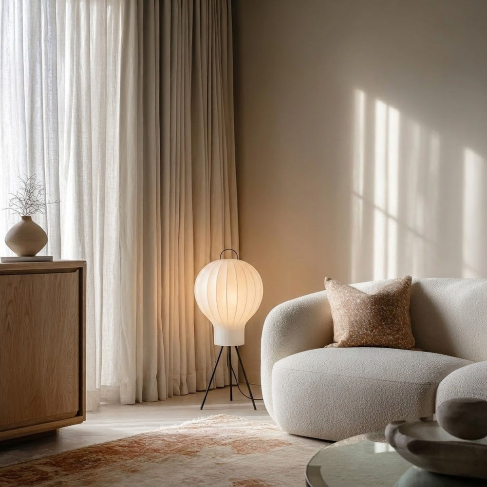 Golvlampa Bubble med rund lampskärm tänd i vardagsrum med beige soffa, gardiner och mjukt naturligt ljus