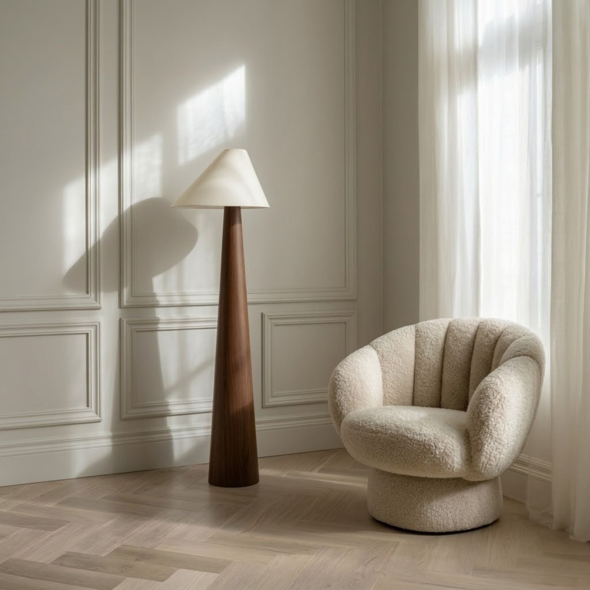 Golvlampa Timber med konformad träbas och vit lampskärm placerad bredvid fåtölj i ljust skandinaviskt vardagsrum.