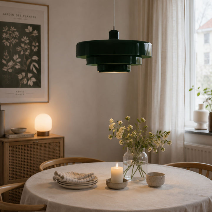 Italia taklampa i grön färg ovanför runt matbord i skandinavisk matsal med ljusa trädetaljer och mjuk belysning.