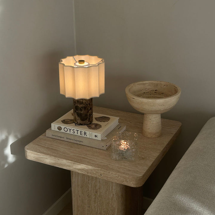 Monolit Breccia portabel bordslampa på sidobord bredvid soffa i ett stilrent och varmt vardagsrum.