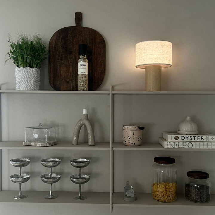 Monolit portabel bordslampa i travertin på hylla i skandinavisk inredning