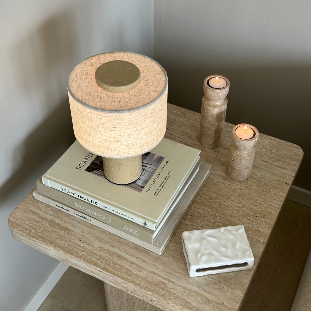 Monolit portabel bordslampa i travertin på sidobord med böcker och ljus