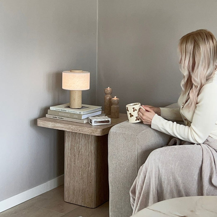 Monolit portabel bordslampa i travertin på sidobord bredvid soffa