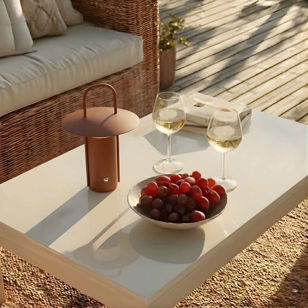 Porto portabel bordslampa i brun finish placerad på soffbord utomhus, i varm kvällsmiljö med naturliga material och skandinavisk design.