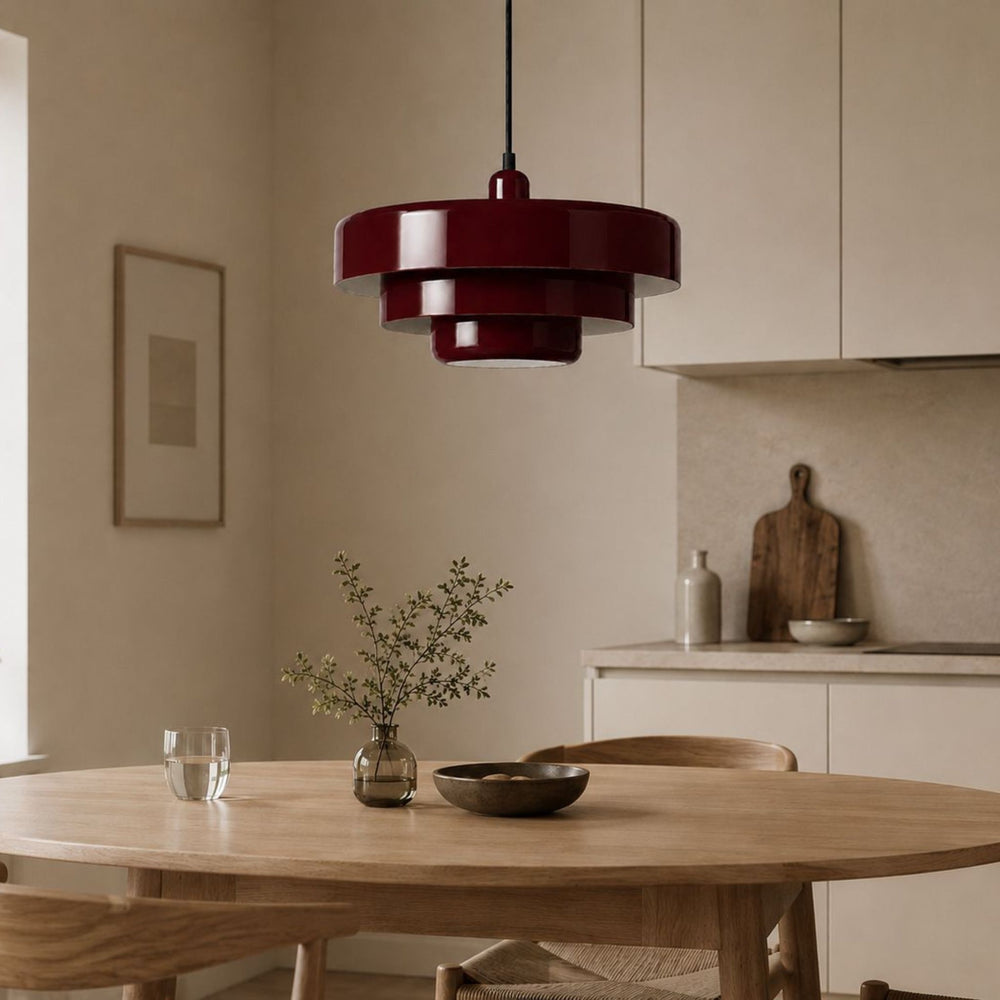 Röd glansig taklampa över matbord i modern skandinavisk köksmiljö med ljusa trädetaljer