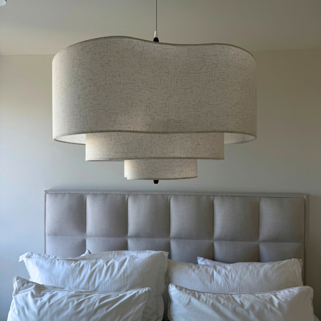 Närbild på Rondo taklampa i beige textil ovanför säng