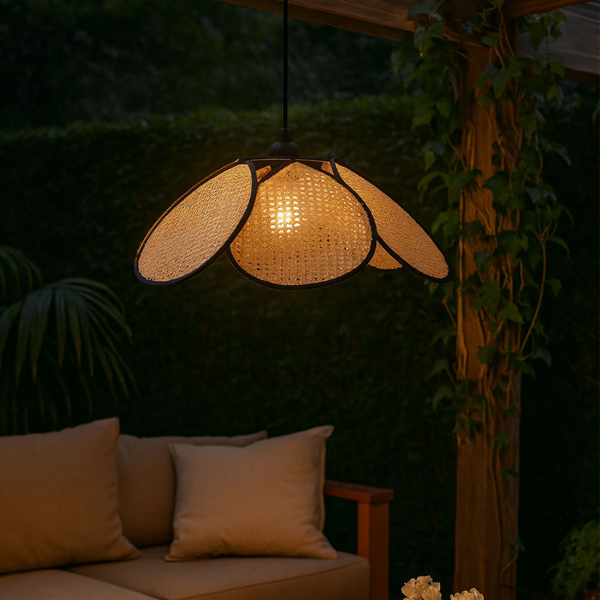 Taklampa Calima tänd i rotting placerad i utomhusmiljö under pergola