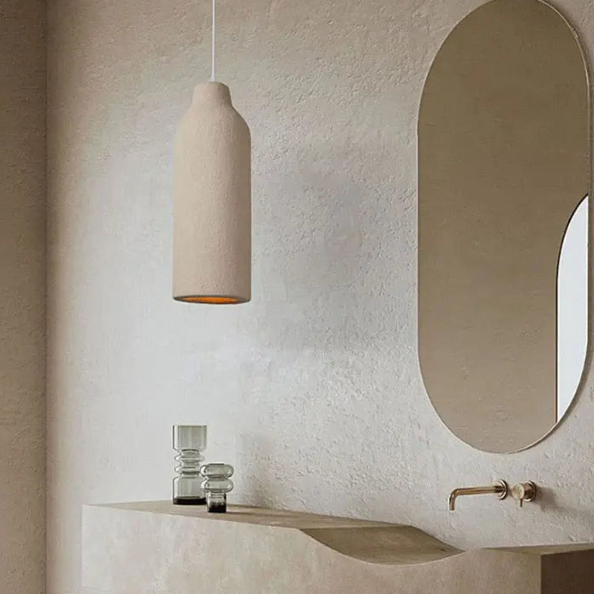 Taklampa Cirrus i beige utförande upphängd i minimalistiskt badrum med mjuka former och varm ljussättning.