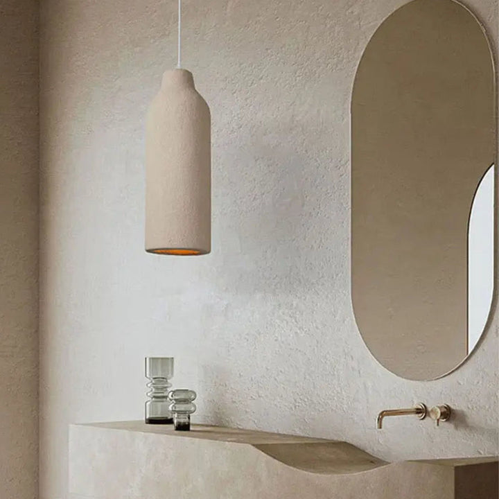 Taklampa Cirrus i beige utförande upphängd i minimalistiskt badrum med mjuka former och varm ljussättning.