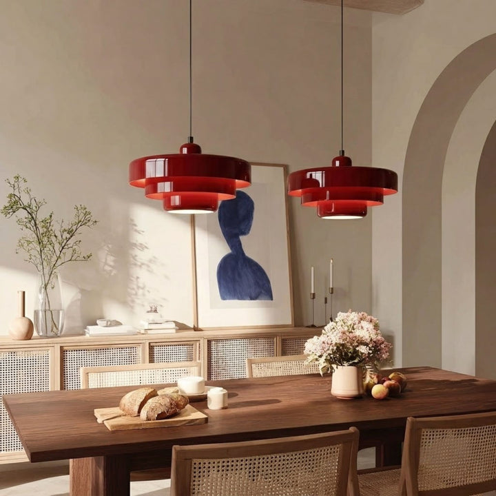 Taklampa Italia i röd metall ovanför matbord med trädetaljer, stolar i rotting och modern inredning
