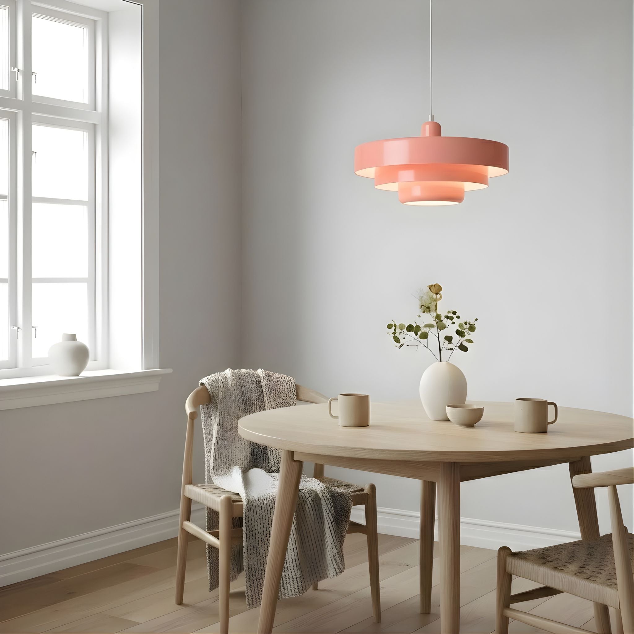 Italia taklampa i rosa finish hängande över runt matbord med stolar i ljus och stilren skandinavisk inredning med mjuka färgtoner.