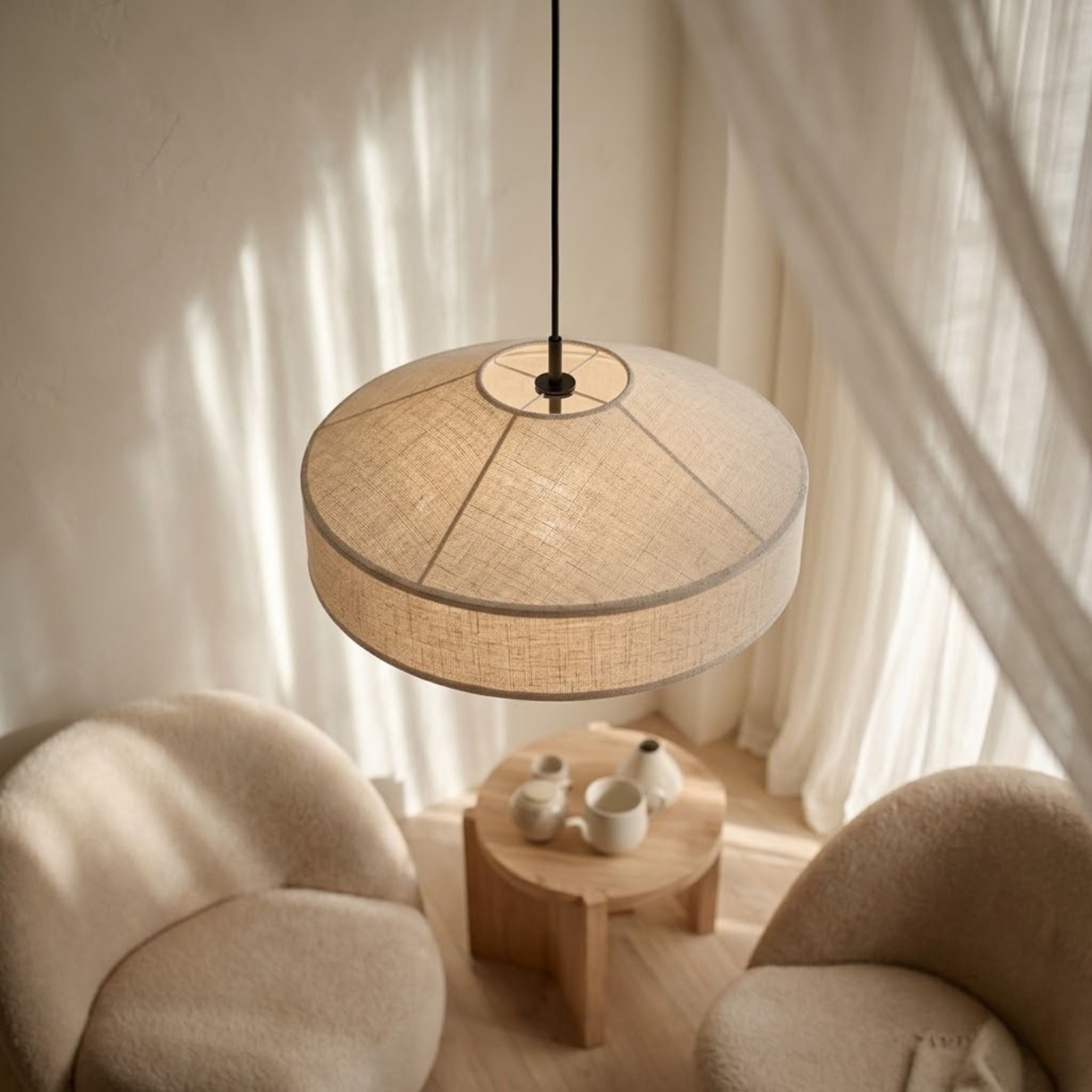 Pagoda taklampa i beige textil med mjuk rund form hängande ovanför sittgrupp med fåtöljer i en varm och harmonisk skandinavisk miljö.