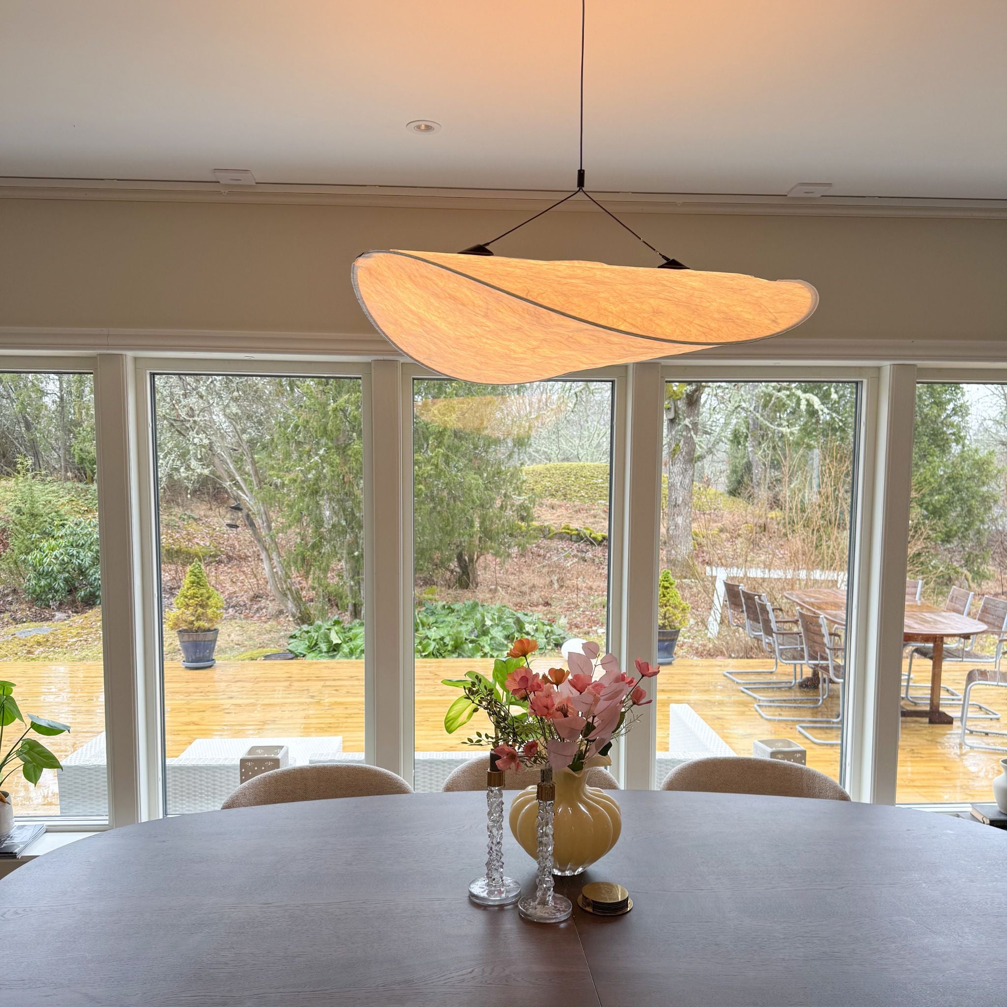 Sailing taklampa i modern organisk design ovanför matbord, stilren skandinavisk inredning med stora fönster och naturligt ljus