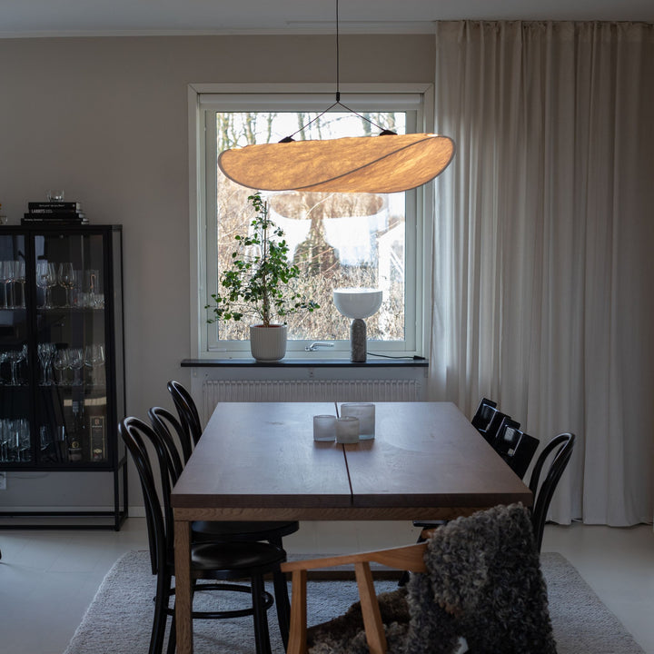 Sailing taklampa i modern organisk design med varm belysning, placerad ovanför träbord i ljus och stilren matplats.